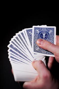 Fanned deck of playing cards in adult hands against a dark background, showcasing skill.